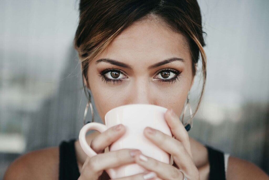 Young lady staring intensely into the camera while sipping coffee made from an espresso machine rental machine.