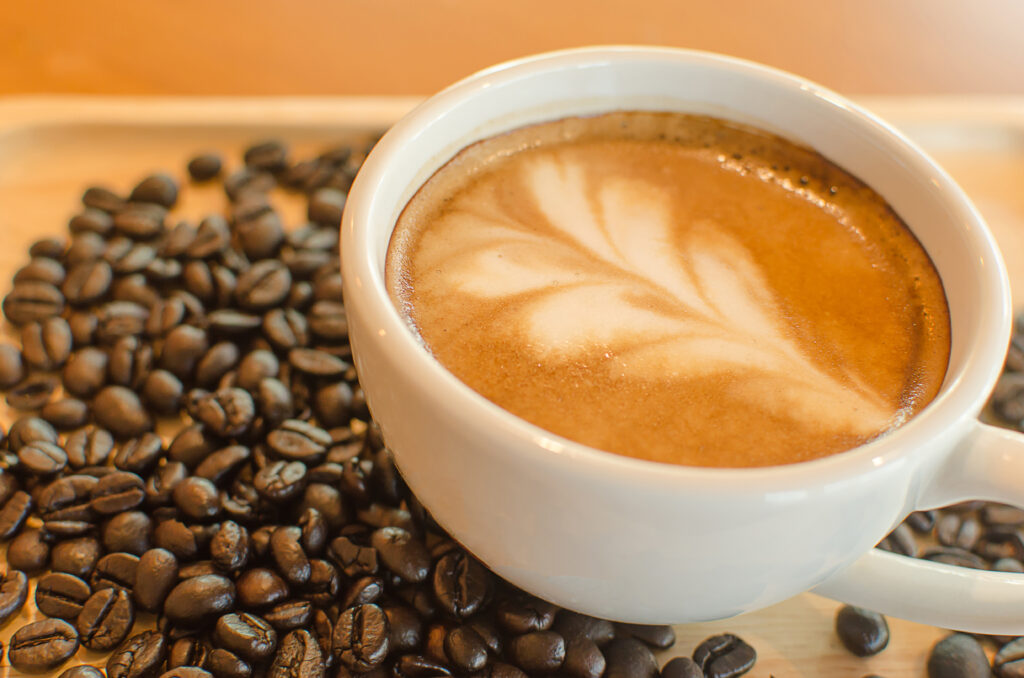 Latte in a white cup surrounded by coffee beans