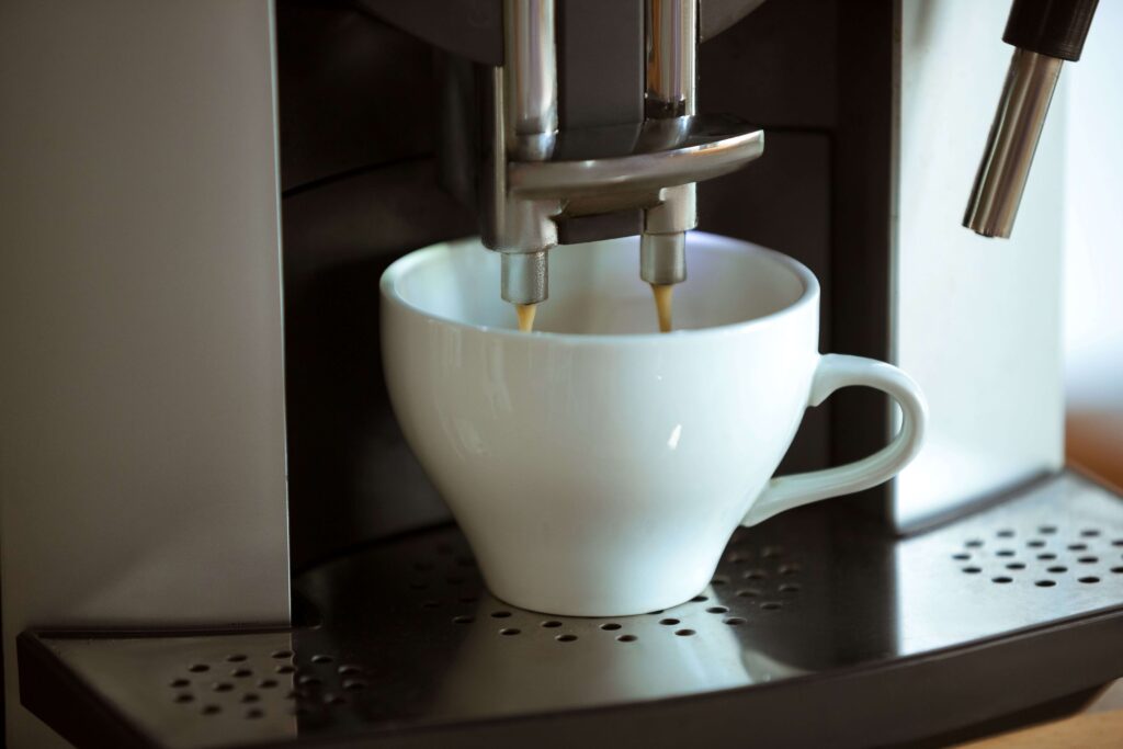 Coffee machine pouring a fresh cup of coffee into a small white coffee cup