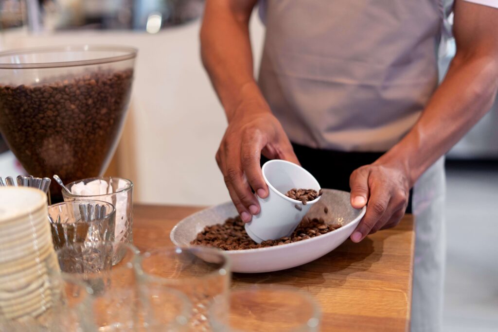 Male barrister measuring out coffee beans to fill espresso makers with grinders to make coffee